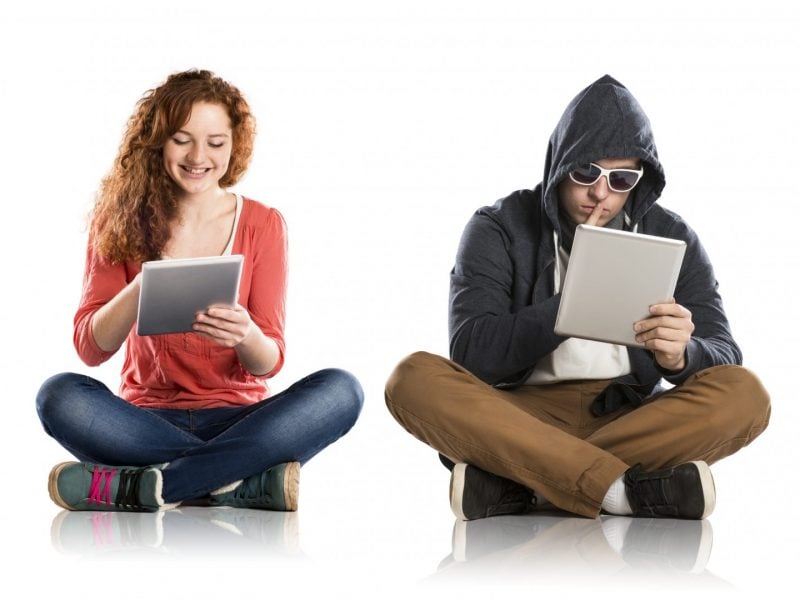 Smiling female and hooded male both using digital tablets Concept of potentional internet danger with teen girl amd man in disguise